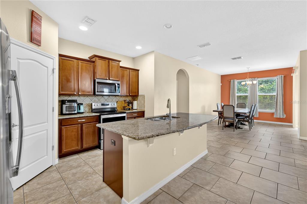 1938 Commander Way Kissimmee, FL 34746 - Photo 7 of 30 a kitchen with stainless steel appliances granite countertop a stove a sink a microwave and a refrigerator