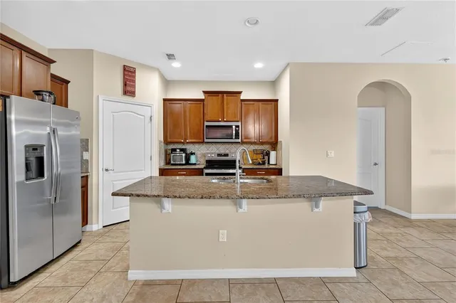 a kitchen with stainless steel appliances granite countertop a refrigerator a stove and a sink