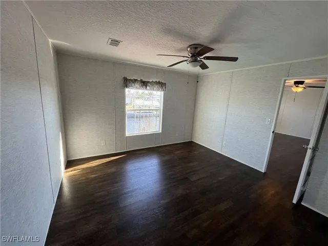 an empty room with wooden floor fan and windows