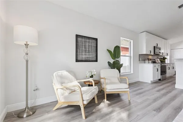 a living room with furniture and a dining table with wooden floor