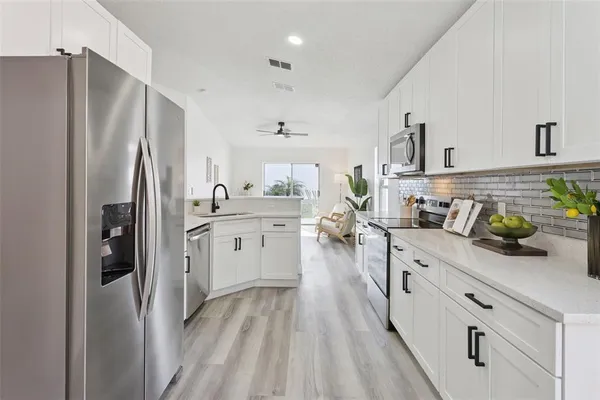 a kitchen with stainless steel appliances a refrigerator sink and white cabinets