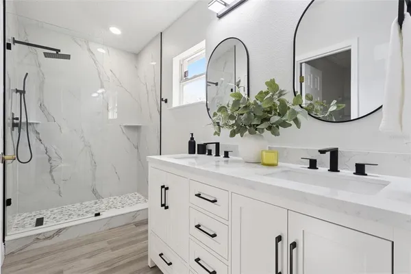 a bathroom with a sink a mirror a vanity and shower