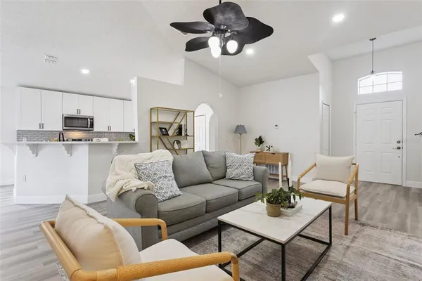 a living room with furniture kitchen view and a chandelier