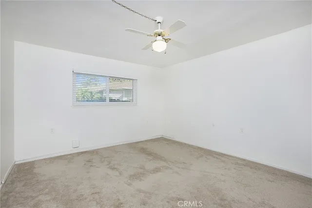 an empty room with a chandelier fan and windows