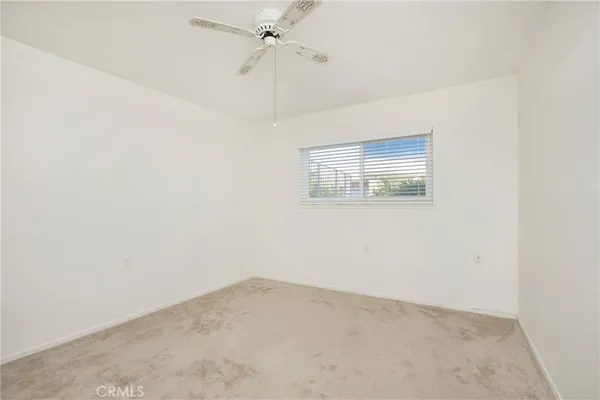 an empty room with a window and a fan