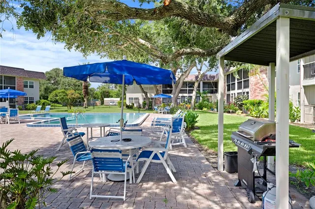 a view of a patio with table and chairs under an umbrella with a small yard