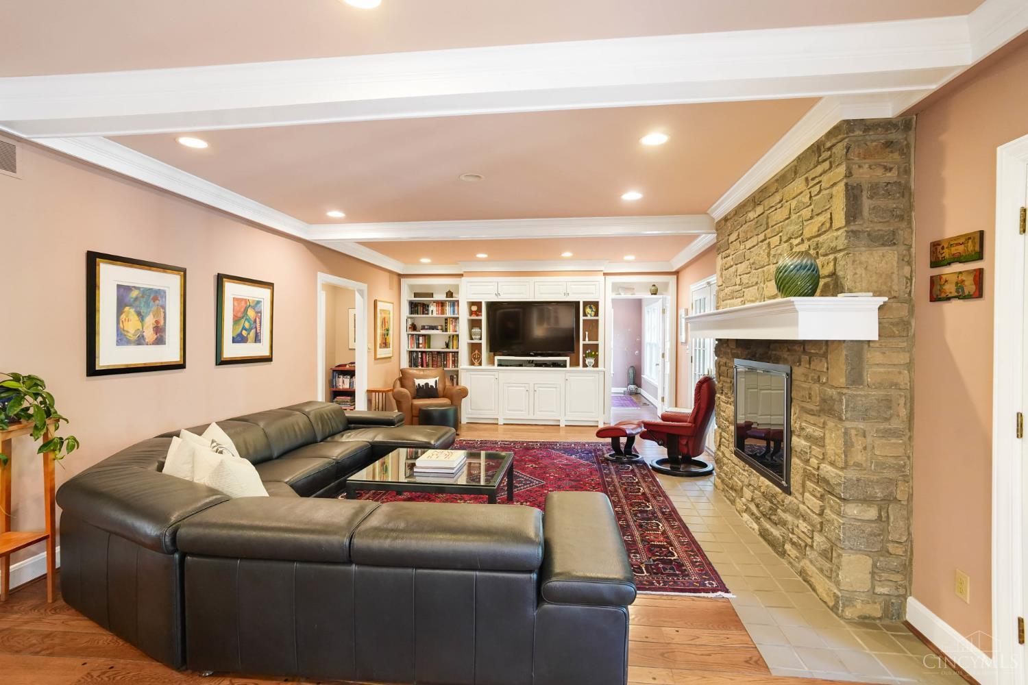 2780 Walsh Road Cincinnati, OH 45208 - Photo 4 of 68 This warm and inviting family room is designed for everyday living and effortless entertaining—anchored by a striking stone fireplace and framed by rich hardwood floors and classic millwork. The generously scaled layout offers multiple seating areas, seamless flow to adjacent spaces and French doors that invite in natural light while opening to outdoor living. Custom built-ins add both function and charm, completing this comfortable yet refined gathering space.