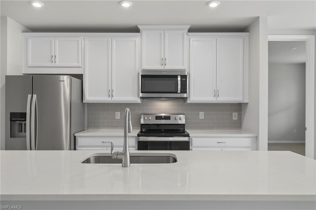 4664 Arboretum Circle, Unit 102 Naples, FL 34112 - Photo 18 of 39 a kitchen with granite countertop white cabinets and stainless steel appliances