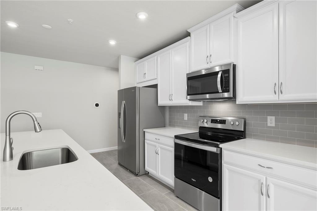 4664 Arboretum Circle, Unit 102 Naples, FL 34112 - Photo 20 of 39 a kitchen with stainless steel appliances a stove a sink a microwave and cabinets