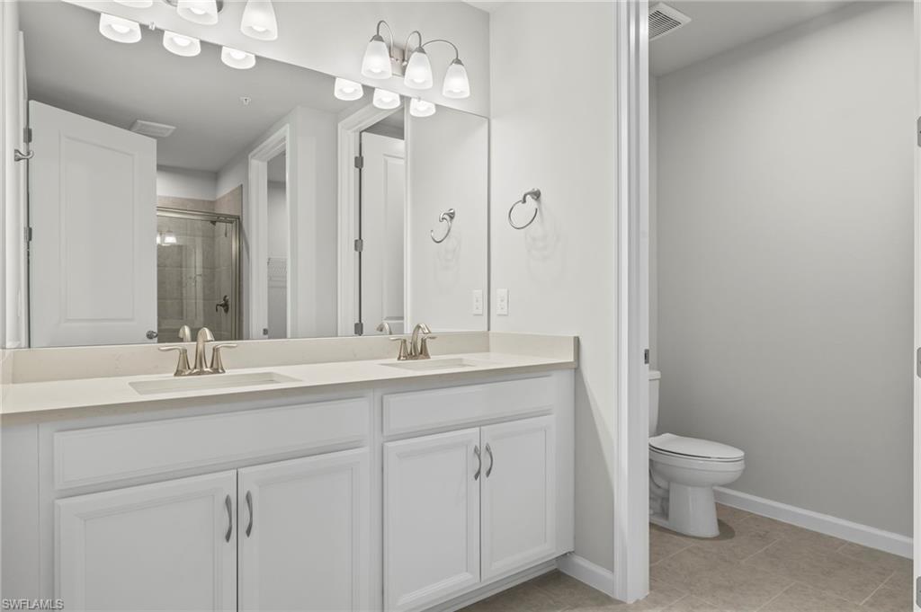 4664 Arboretum Circle, Unit 102 Naples, FL 34112 - Photo 32 of 39 a bathroom with a double vanity sink and a mirror