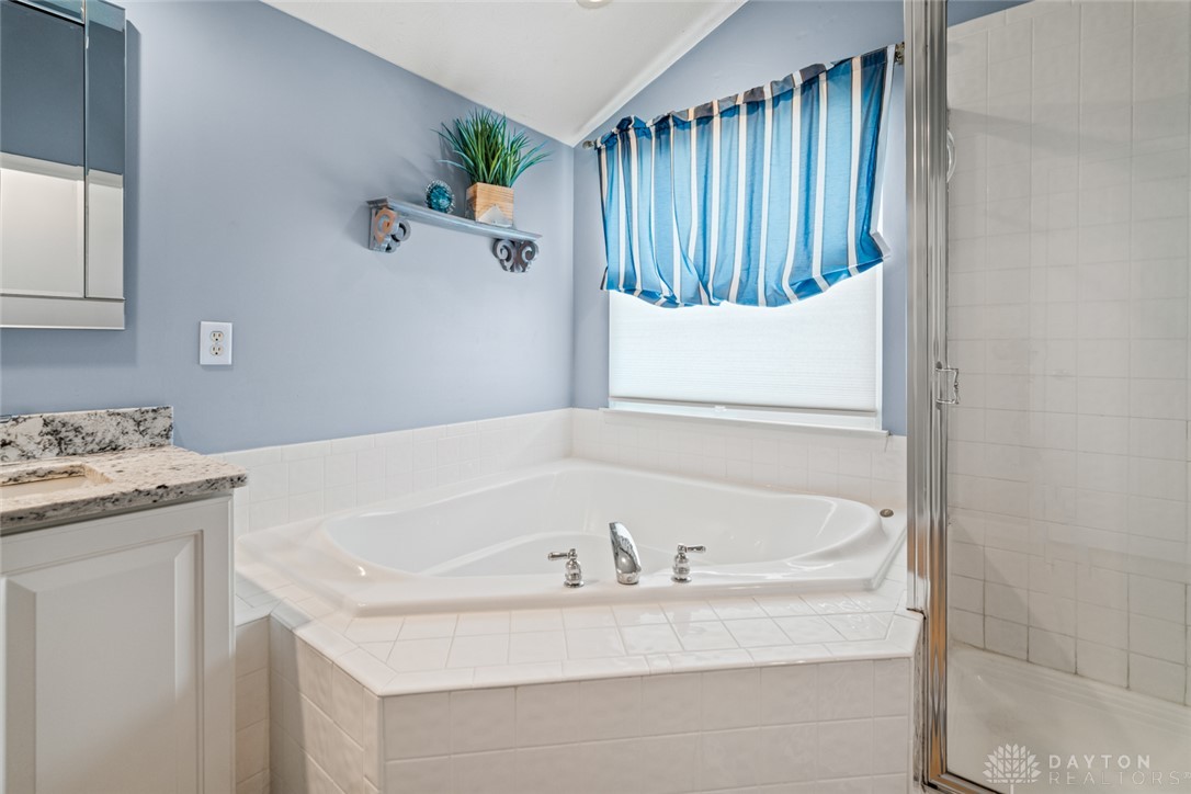 55 Janney Lane Springboro, OH 45066 - Photo 27 of 38 This primary bathroom features a corner soaking tub and a separate shower, complemented by a vanity with granite counters.
