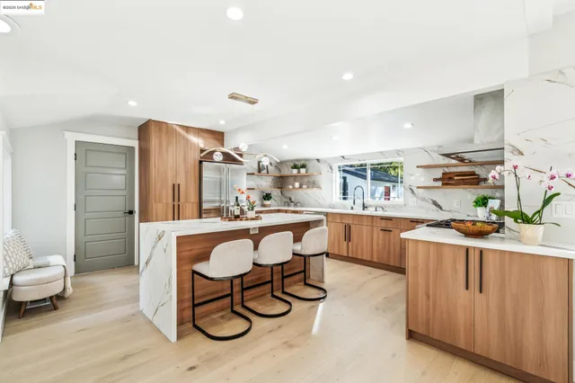 a living room with stainless steel appliances furniture a rug and a kitchen view