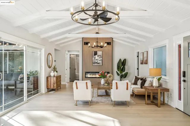 a living room with furniture a chandelier and a dining table with wooden floor
