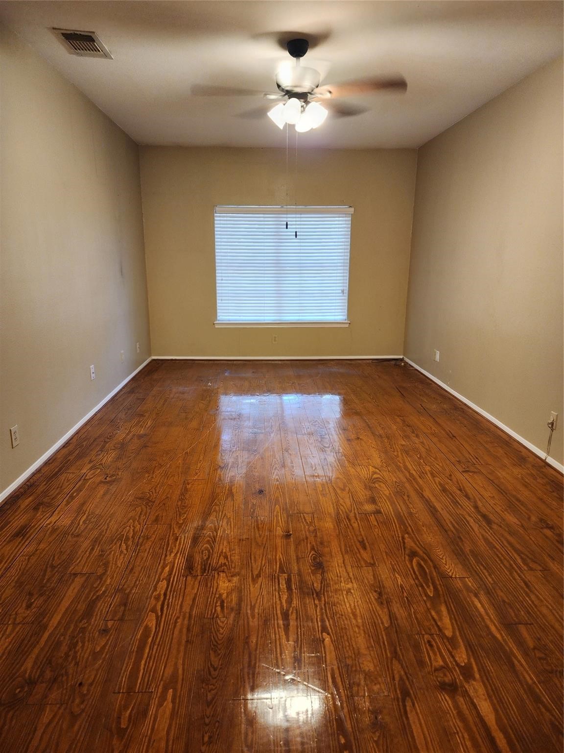 7399 Regency Square Court, Unit 7399 Houston, TX 77036 - Photo 12 of 27 an empty room with wooden floor chandelier fan and windows