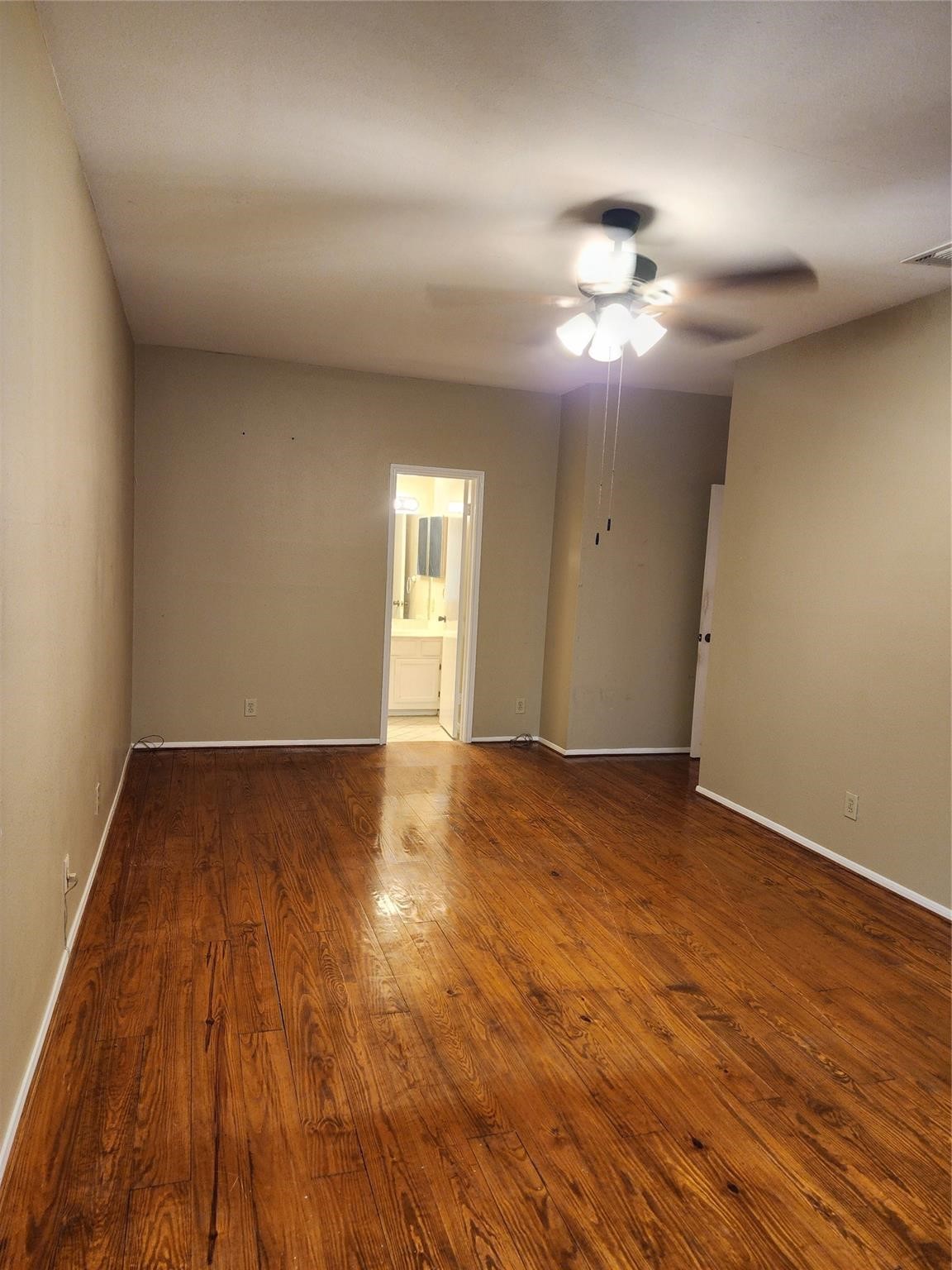 7399 Regency Square Court, Unit 7399 Houston, TX 77036 - Photo 13 of 27 a view of an empty room with wooden floor and a fan