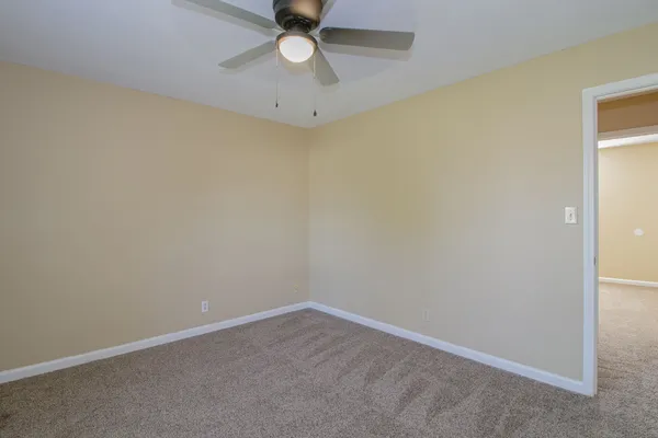 an empty room with a ceiling fan and carpet