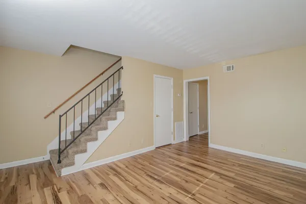 a view of an empty room with wooden floor and stairs