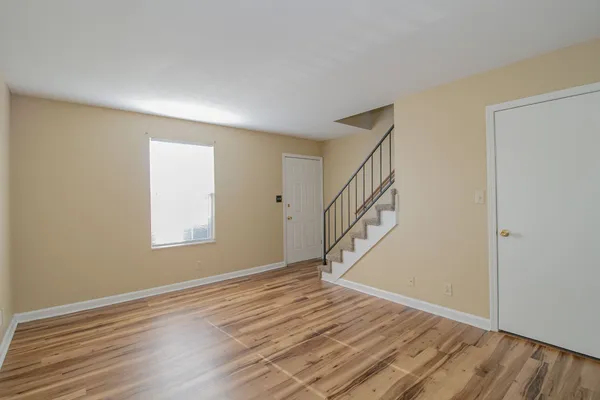 a view of an empty room with wooden floor and a window