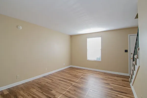 a view of an empty room with wooden floor and a window