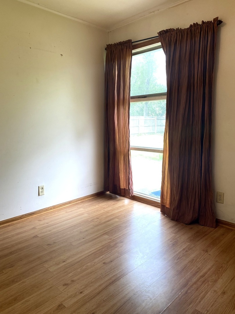 614 North Reed Street Joliet, IL 60435 - Photo 13 of 16 an empty room with wooden floor and windows with curtains