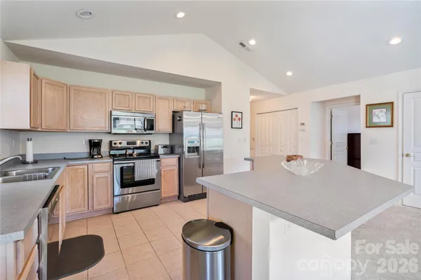 a kitchen with stainless steel appliances granite countertop a sink a stove a refrigerator cabinets and chairs