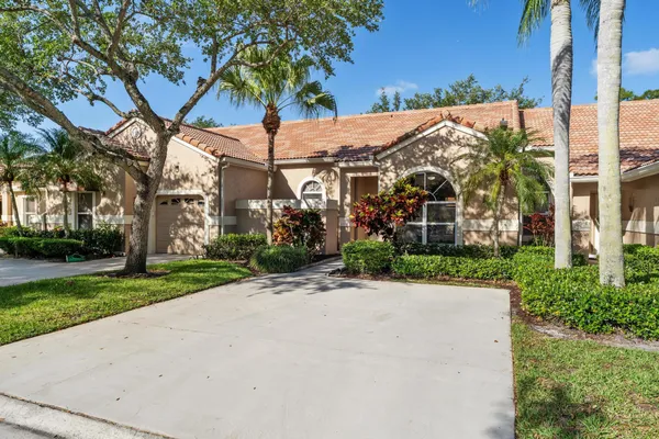 a view of a white house with a big yard and potted plants