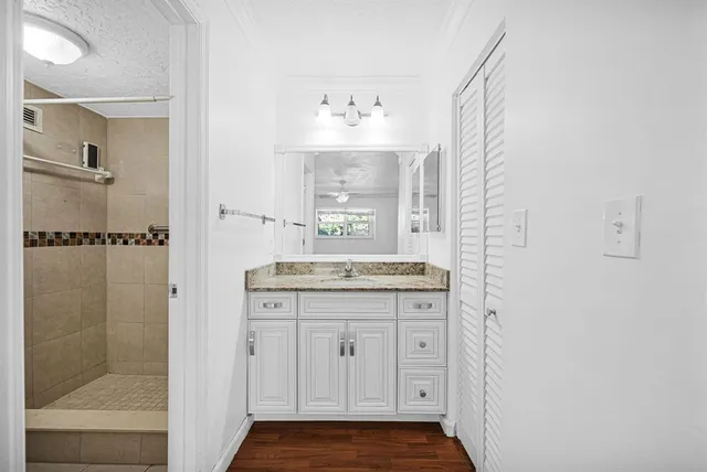 a bathroom with a granite countertop sink a mirror and a shower