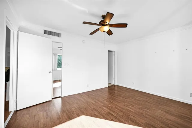 a view of empty room with wooden floor and fan