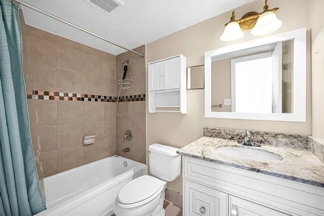 a bathroom with a granite countertop sink a toilet and shower