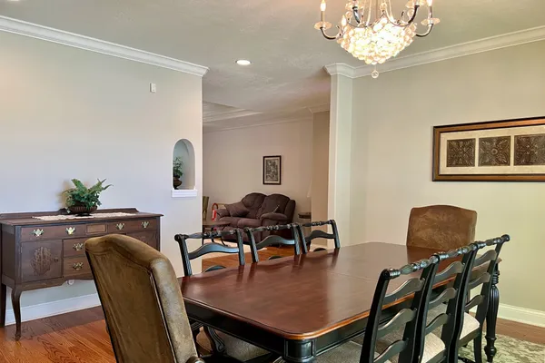 a kitchen with granite countertop a stove a sink a dining table and chairs with wooden floor