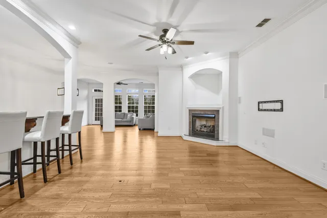 a view of an empty room with chandelier fan and wooden floor