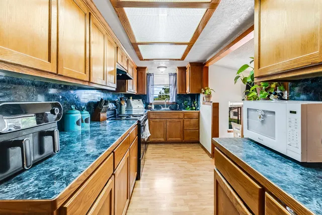 a kitchen with stainless steel appliances granite countertop lots of counter top space wooden floor and windows