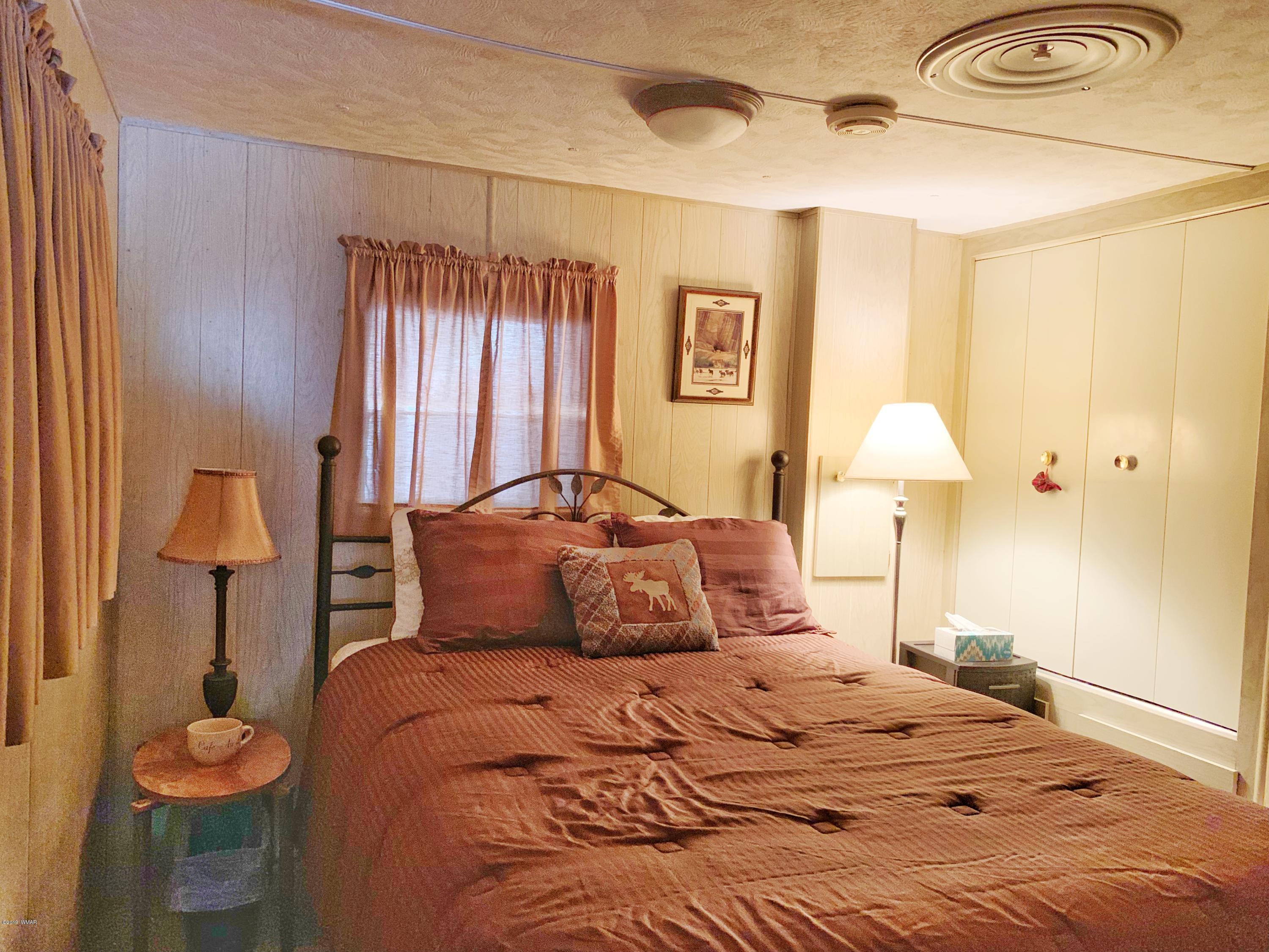2128 Cottontail Road Overgaard, AZ 85933 - Photo 8 of 18 a bedroom with a bed and a lamp