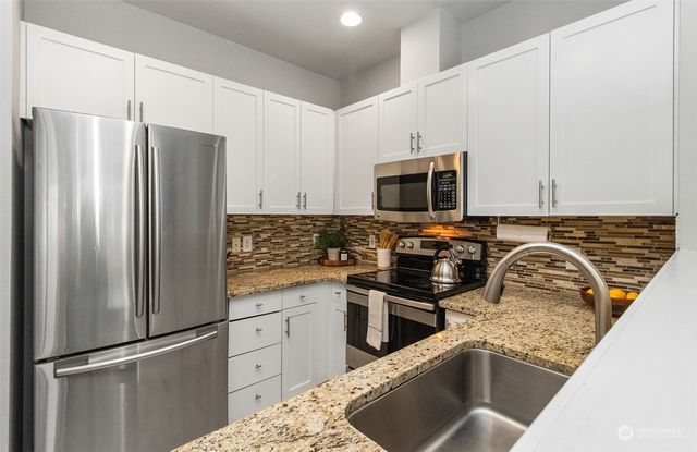 a kitchen with stainless steel appliances granite countertop a refrigerator stove and sink
