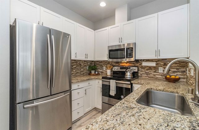 a kitchen with stainless steel appliances granite countertop a refrigerator stove and sink