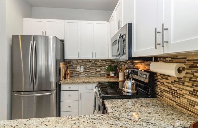 a kitchen with stainless steel appliances granite countertop a refrigerator stove and sink