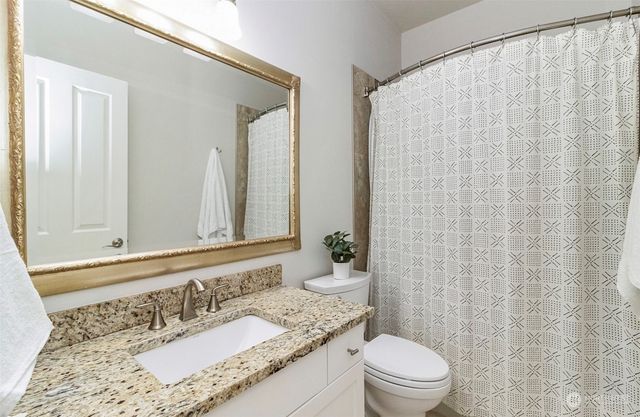 a bathroom with a granite countertop sink a toilet and a mirror