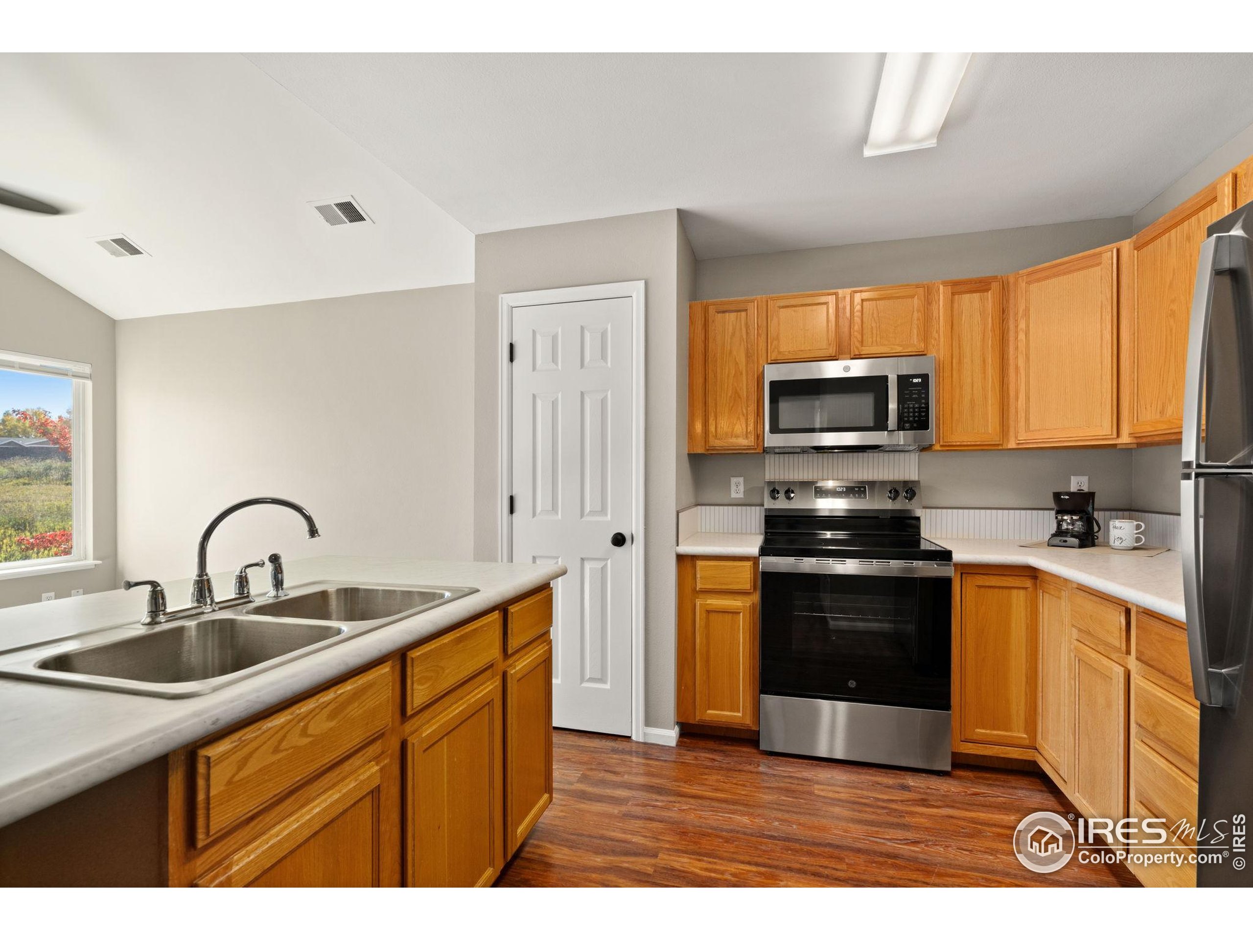 1021 Rolland Moore Drive, Unit F Fort Collins, CO 80526 - Photo 11 of 29 a kitchen with stainless steel appliances granite countertop a sink a stove a refrigerator cabinets and a window