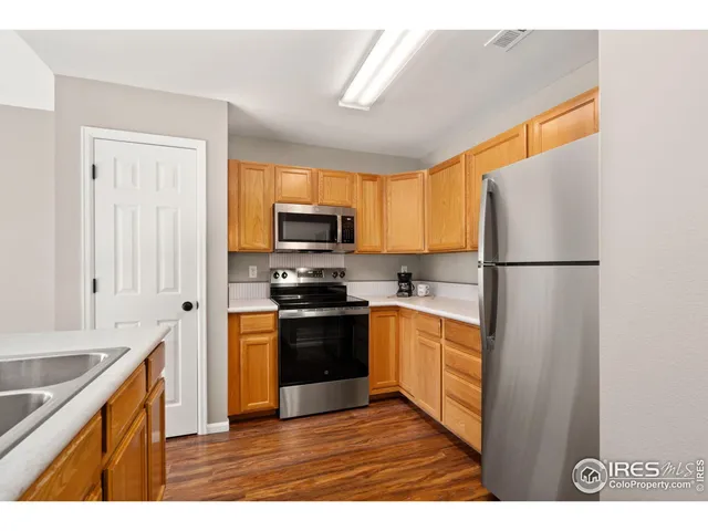 a kitchen with stainless steel appliances granite countertop a sink a stove a refrigerator cabinets and a window
