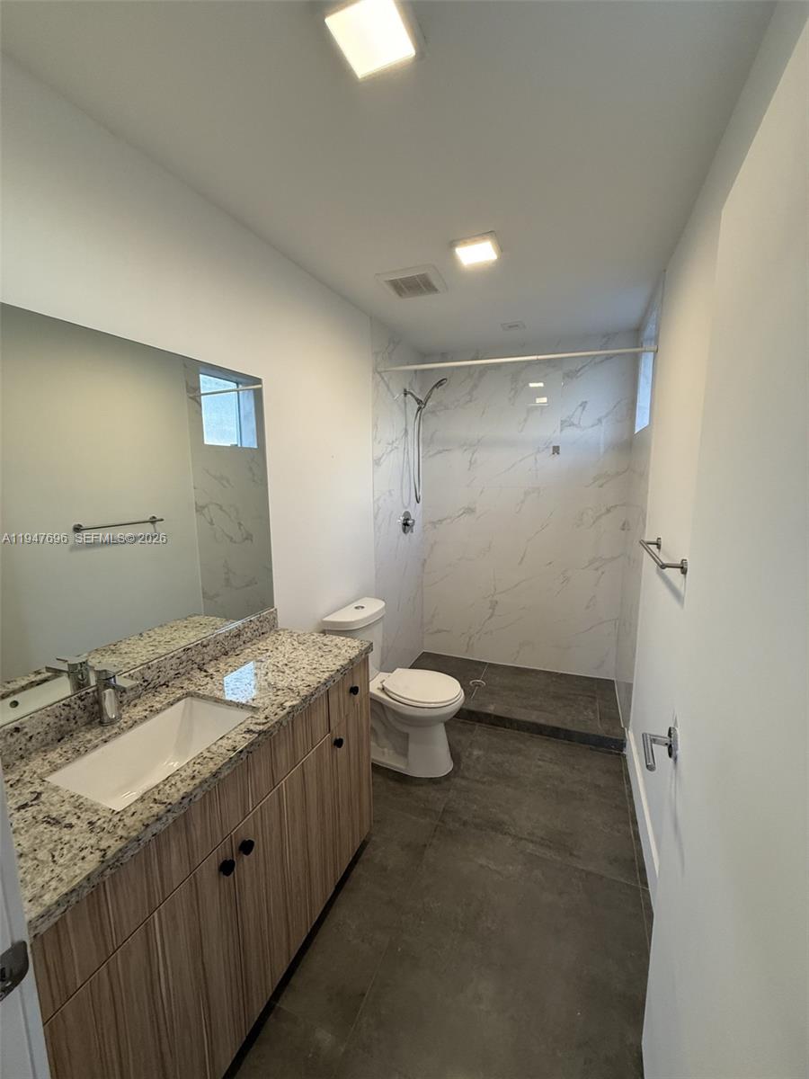2010 Southwest 25th Terrace, Unit 302 Miami, FL 33133 - Photo 10 of 16 a bathroom with a granite countertop sink a toilet and a mirror