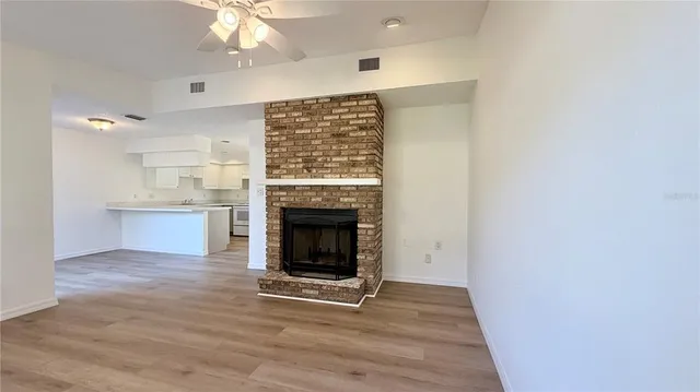 an empty room with wooden floor a fireplace and windows