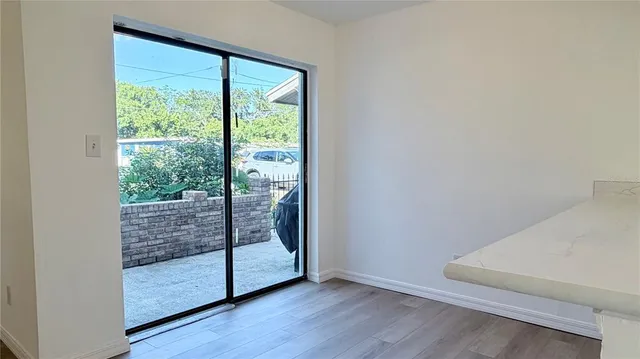 a view of an empty room with wooden floor and windows