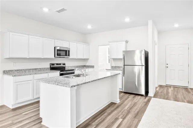 a kitchen with a refrigerator a microwave a sink and cabinets