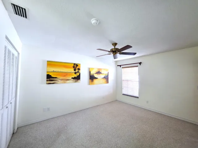 an empty room with windows and ceiling fan