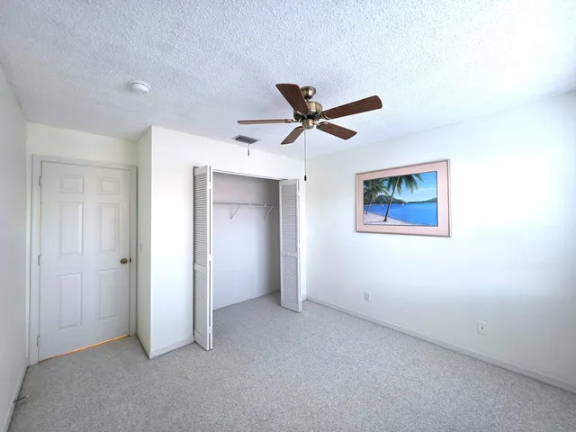 an empty room with closet and a ceiling fan