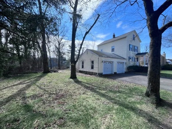 a view of a big house with large tree and wooden fence
