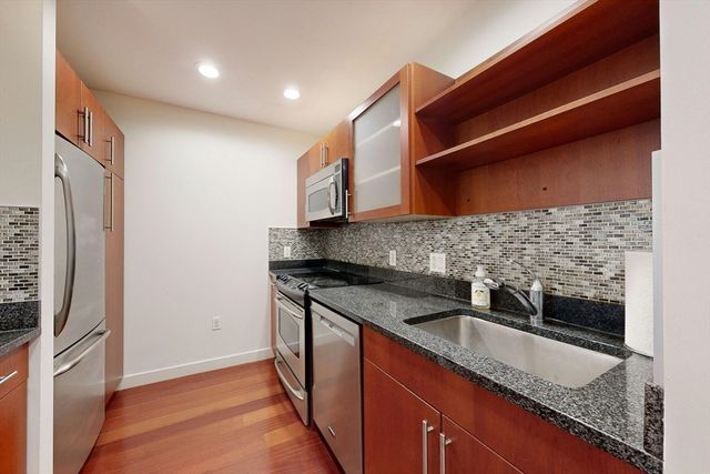 a kitchen with stainless steel appliances granite countertop a sink and a refrigerator