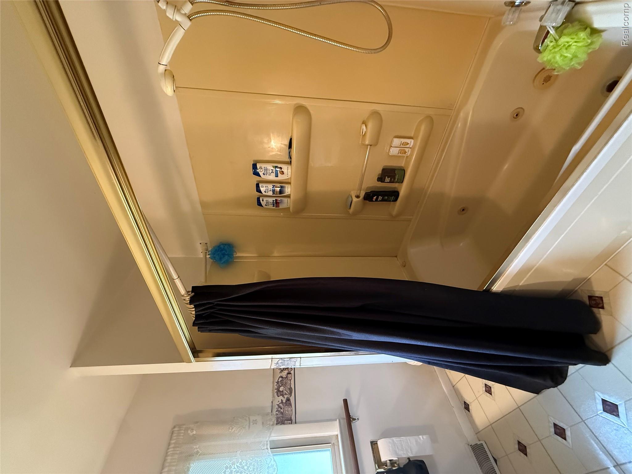 6526 State Road Millington, MI 48746 - Photo 12 of 29 Alcove bathtub with integrated jets and a shower fixture, featuring a built-in shelf unit and white tile flooring with brown accents