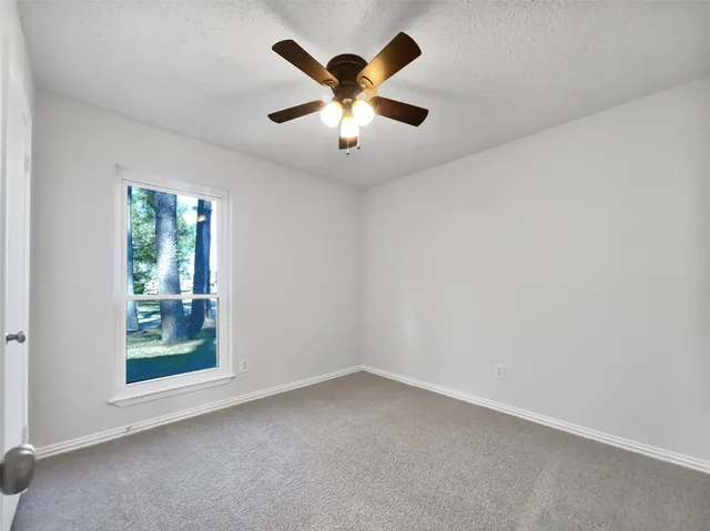 an empty room with window and ceiling fan