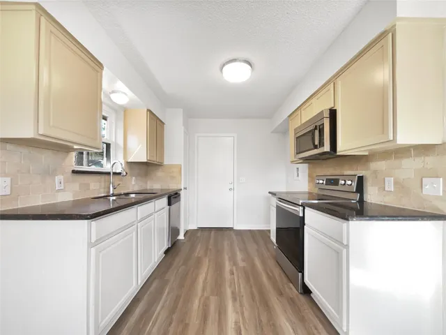 a kitchen with stainless steel appliances granite countertop wooden cabinets a stove top oven a sink and dishwasher